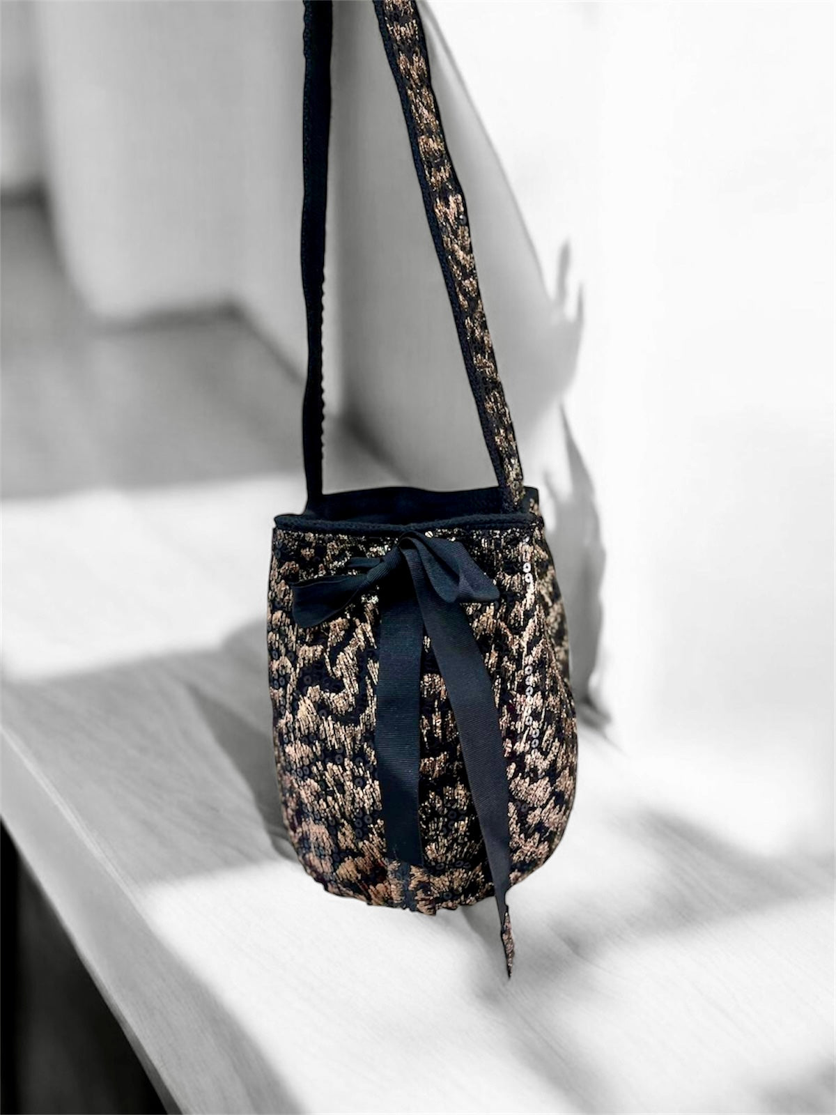 Leopard print handbag with a black ribbon on a light wooden surface