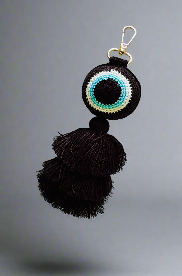 Black tassel keychain with colorful circular design on a gray background
