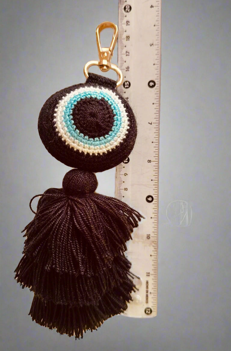 Crocheted keychain with tassels next to a ruler on a gray background