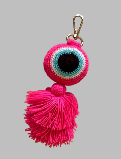 Pink evil eye keychain with tassels on a gray background