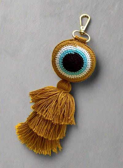 Keychain with eye design and tassels on a light gray background
