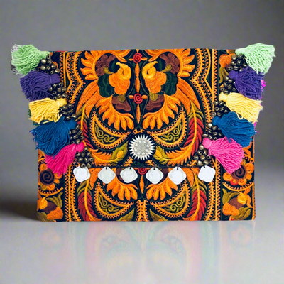 Colorful embroidered clutch with tassels on a gray background