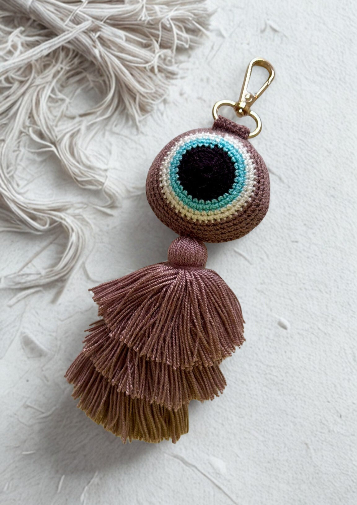 Crocheted keychain with tassel on a textured white background